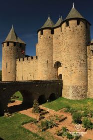 Bridge over a garden to enter the Comtal Castle of Carcassonne, blue skies and medieval towers.