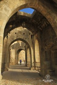 Medieval entrance of the Carcassonne Castle in France with a man walking through.