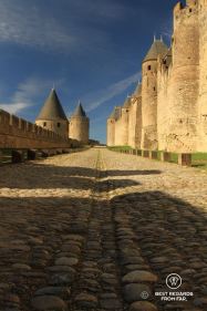 Straight empty coble ramparts with medieval towers and walls on both sides, Carcassonne, France.