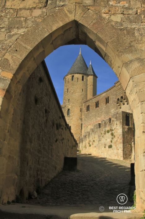 Medieval gate with cobble stoned street leading to a medieval tower in France.