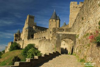 Woman walking through the Porte d'Aude in the medieval city of Carcassonne in France on a sunny day.