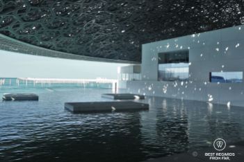 Modern buildings with water and a honeycomb roof, sunlight piercing through. Louvre Abu Dhabi.