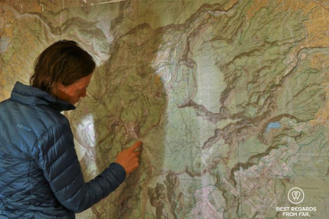 Hiking in technical clothes planning the exclusive multiday hike through the 3 cirques, Réunion Island, on a large wall map of the island.