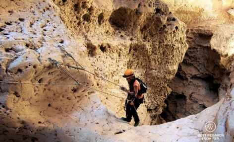 Photographer Claire Lessiau climbing up from the Seventh Hole Cave in Oman, using roping techniques.