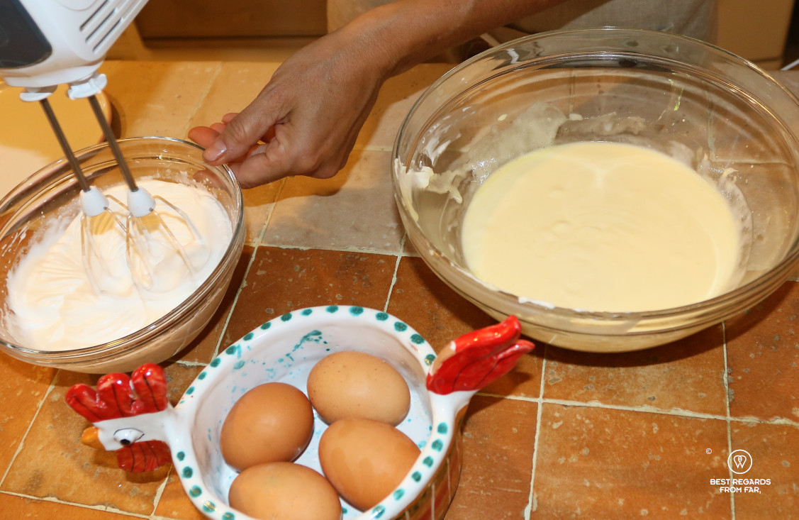 Recipe of tiramisu: eggs and two bowls, one containing mascarpone and egg yolk cream, and the other in which egg whites are stiffened.